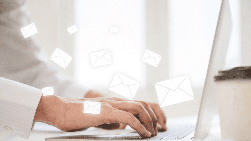 fingers typing on keyboard and envelopee icons scattered indicating the person is sending an email